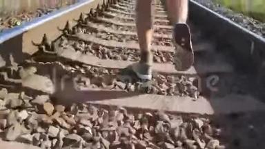男足在铁轨上的铁轨之间奔跑。 在铁路枕木上慢跑的跑步者。 运动腿
